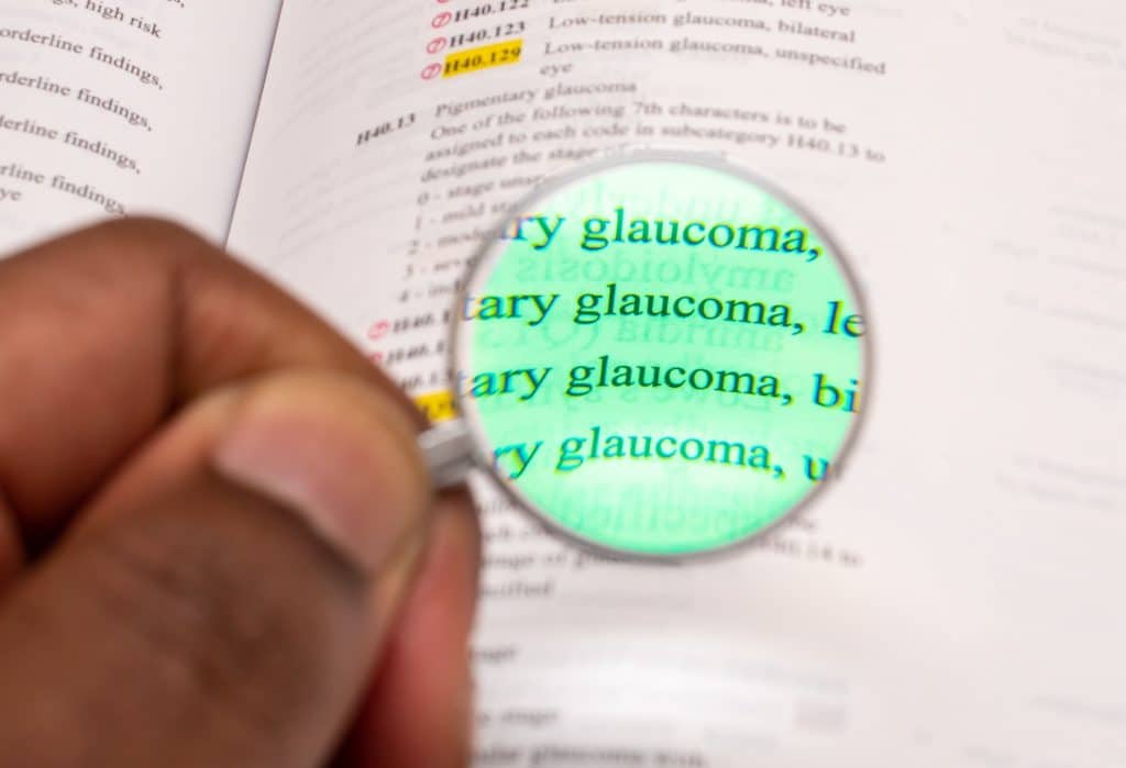 African American man using magnifying glass to look at word glaucoma